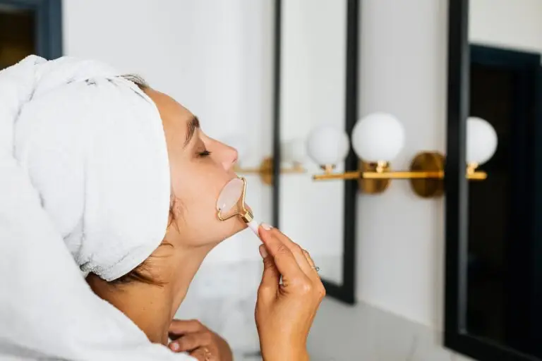 A serene woman with a towel on her head using a face roller in a spa setting, reflecting self-care and relaxation.